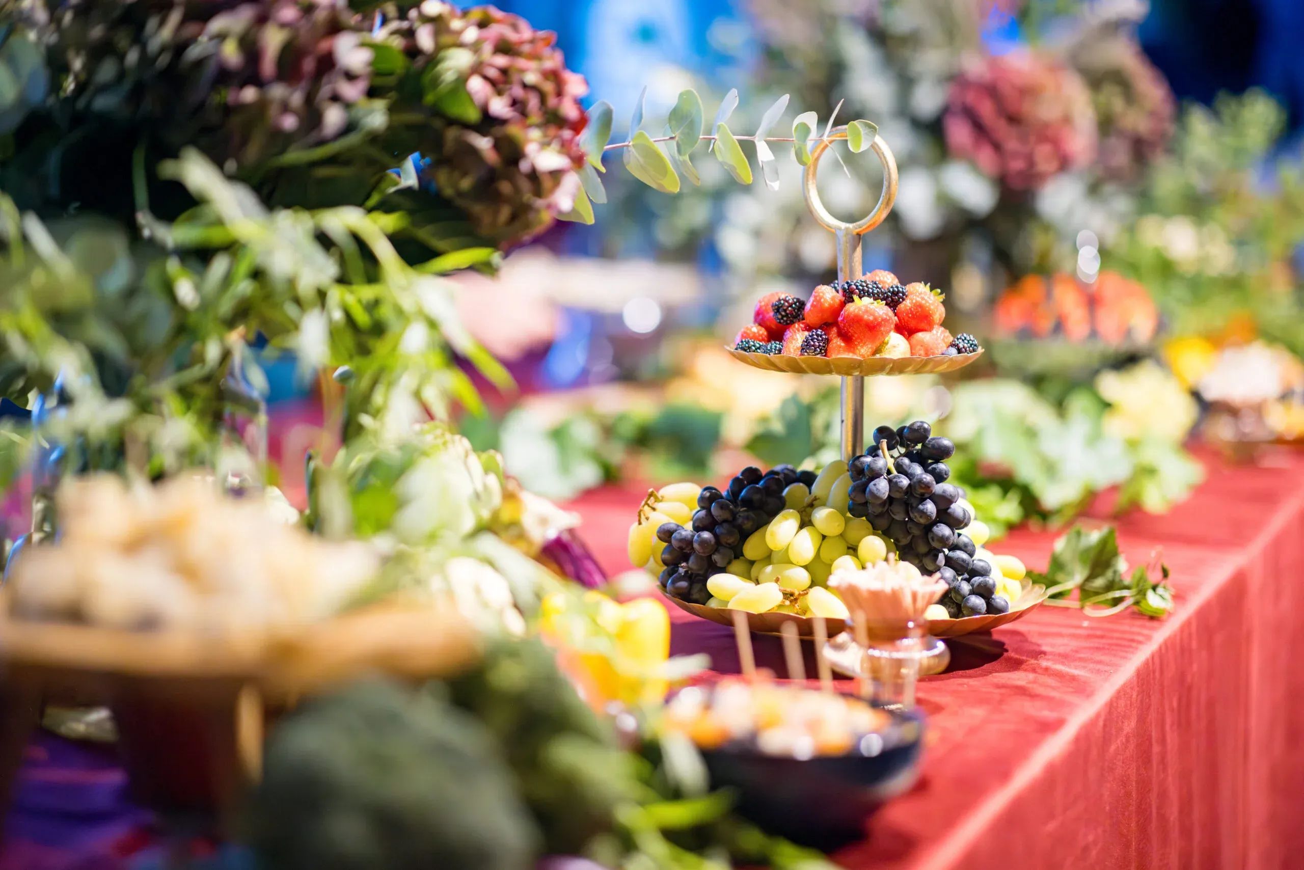  Op de uitgebreide buffettafel staat een fruitplateau met twee lagen, omringd door bloemen en kazen.