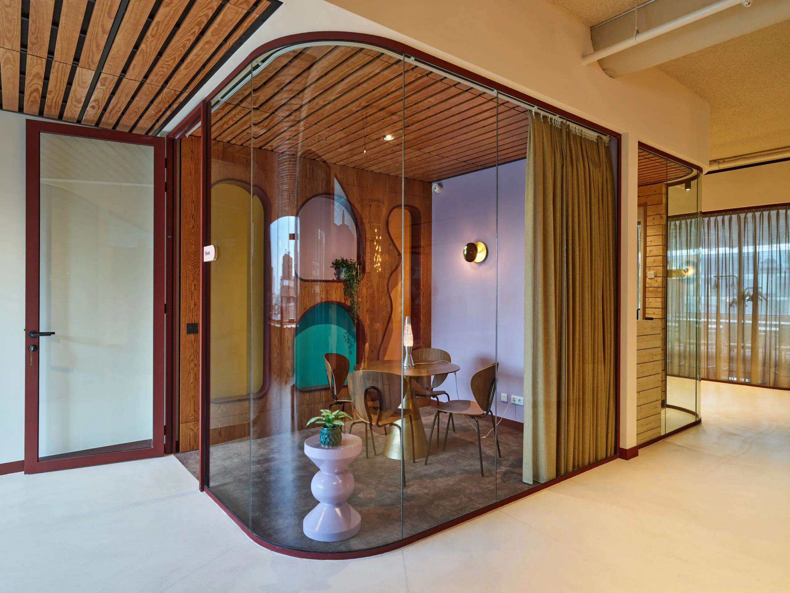 Een levendig, modern kantoorinterieur met gebogen glazen wanden, houten plafond en kleurrijke, minimalistische inrichting.