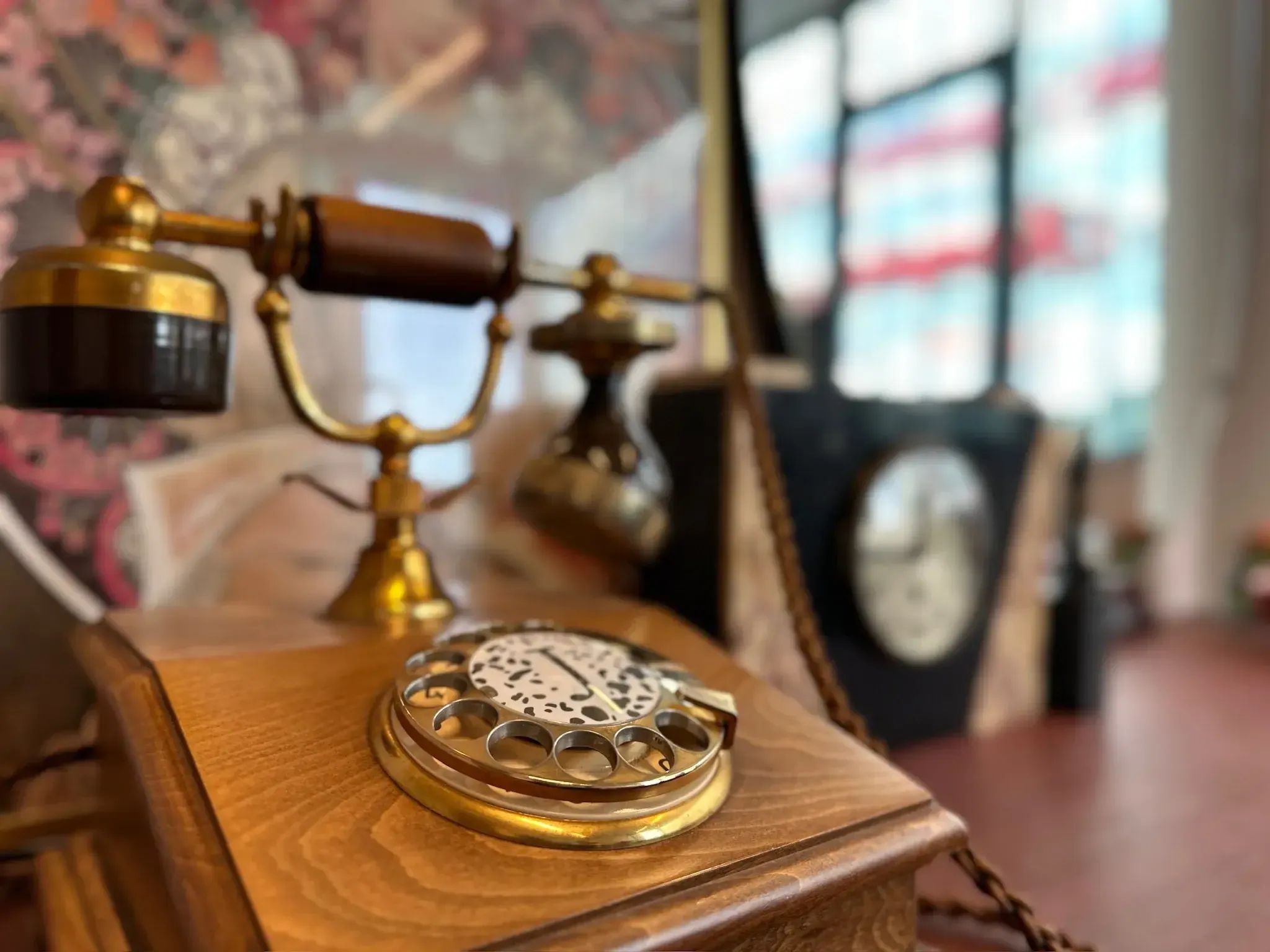 Antieke koperen en houten draaitelefoon met sierlijke details op een gepolijste houten tafel.