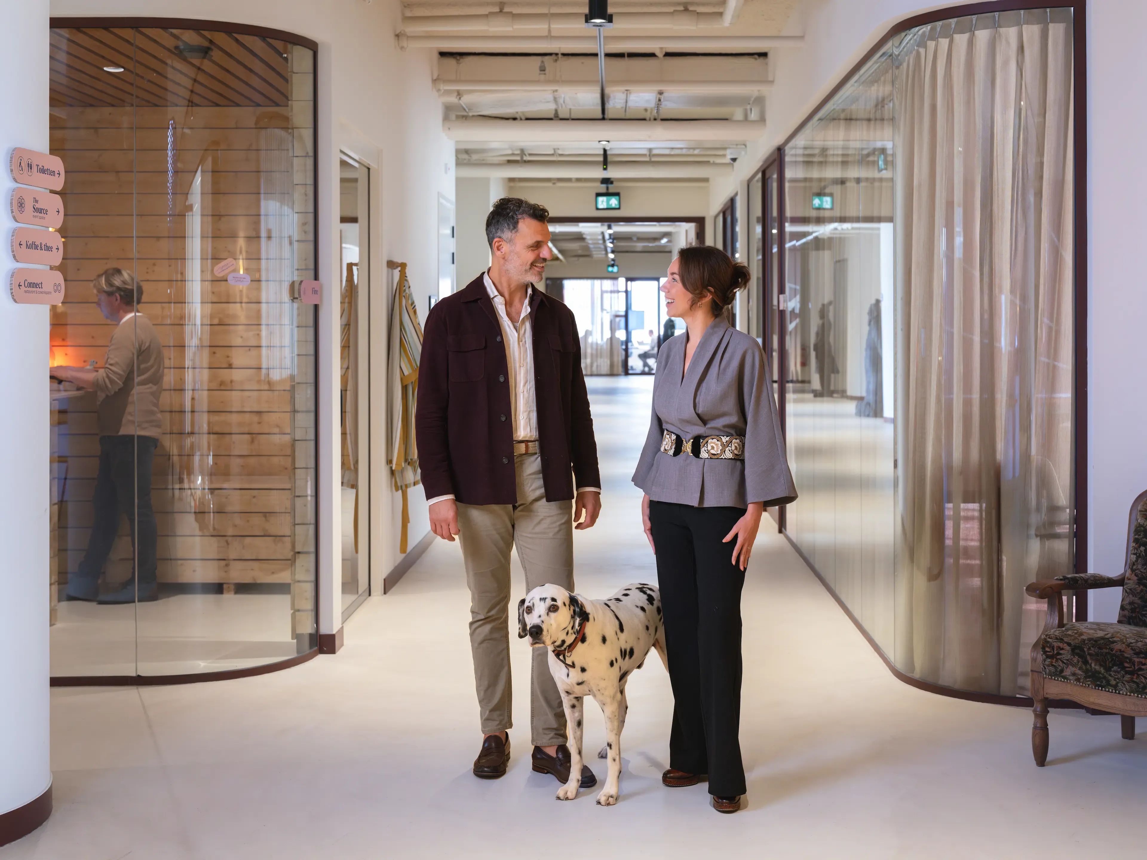 Man en vrouw lopen met een dalmatiër door een moderne coworking space in Utrecht Centraal.