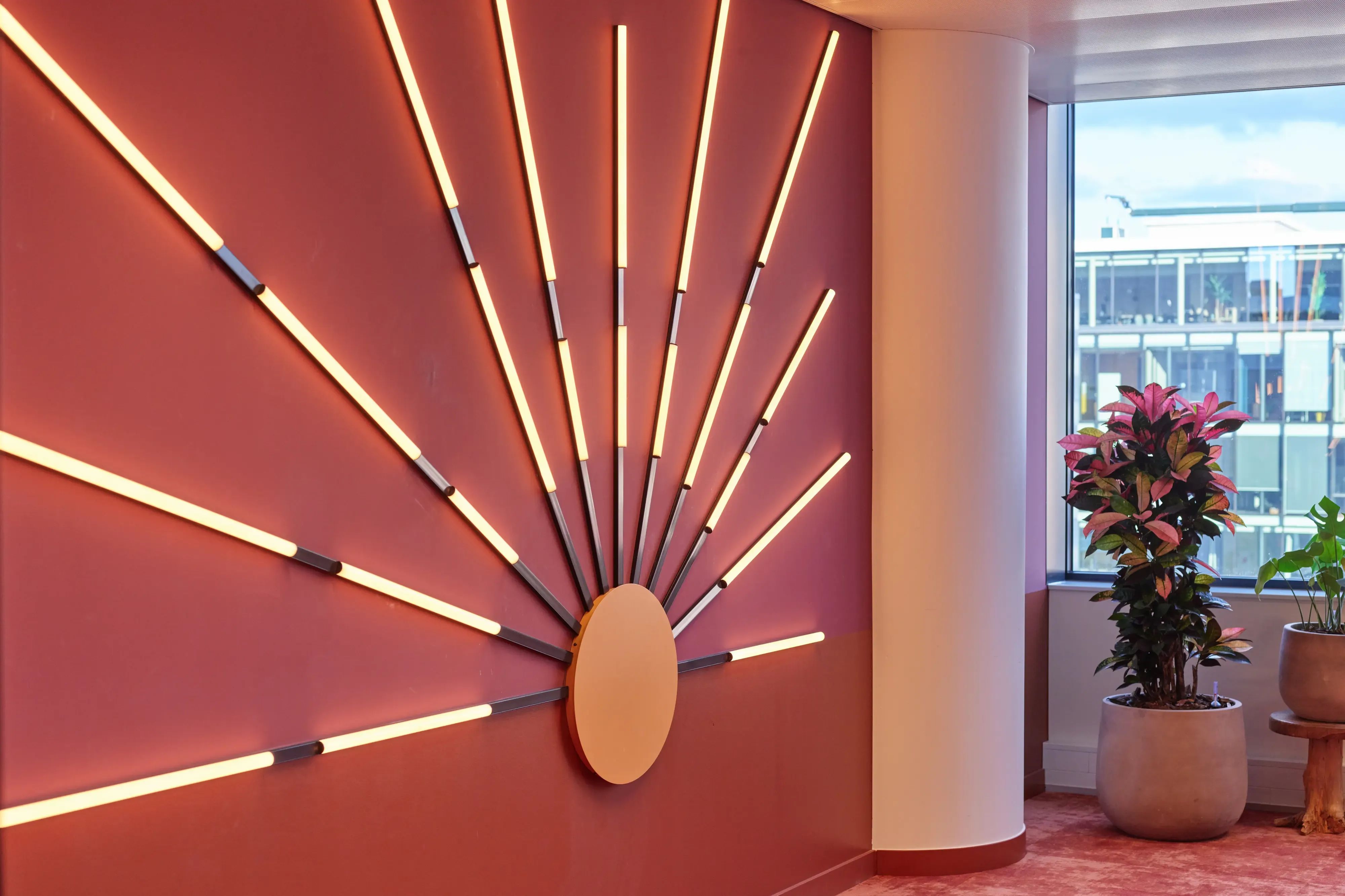 Modern interieur met een roze muur met een LED-lamp in de vorm van een zonnestraal.