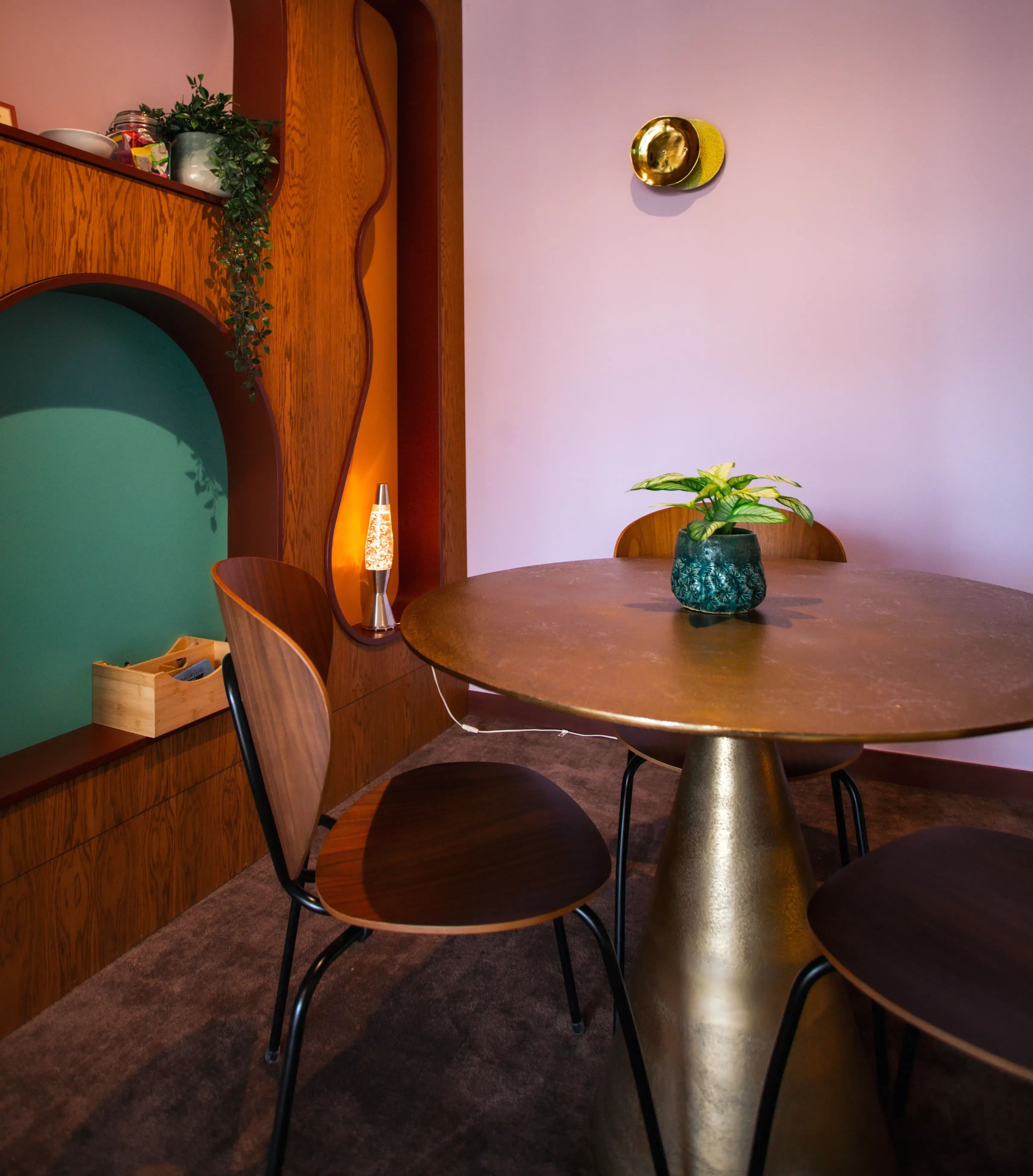 Moderne eethoek met een gouden ronde tafel, twee stoelen en paarse en blauwgroene muren.