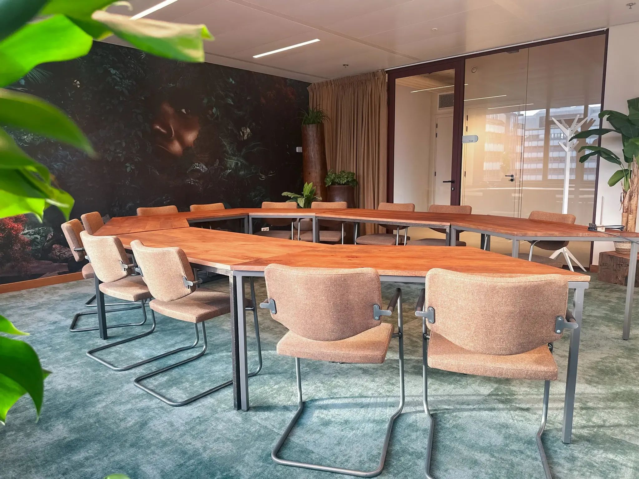 Moderne vergaderruimte met een grote U-vormige houten tafel en comfortabele stoelen.