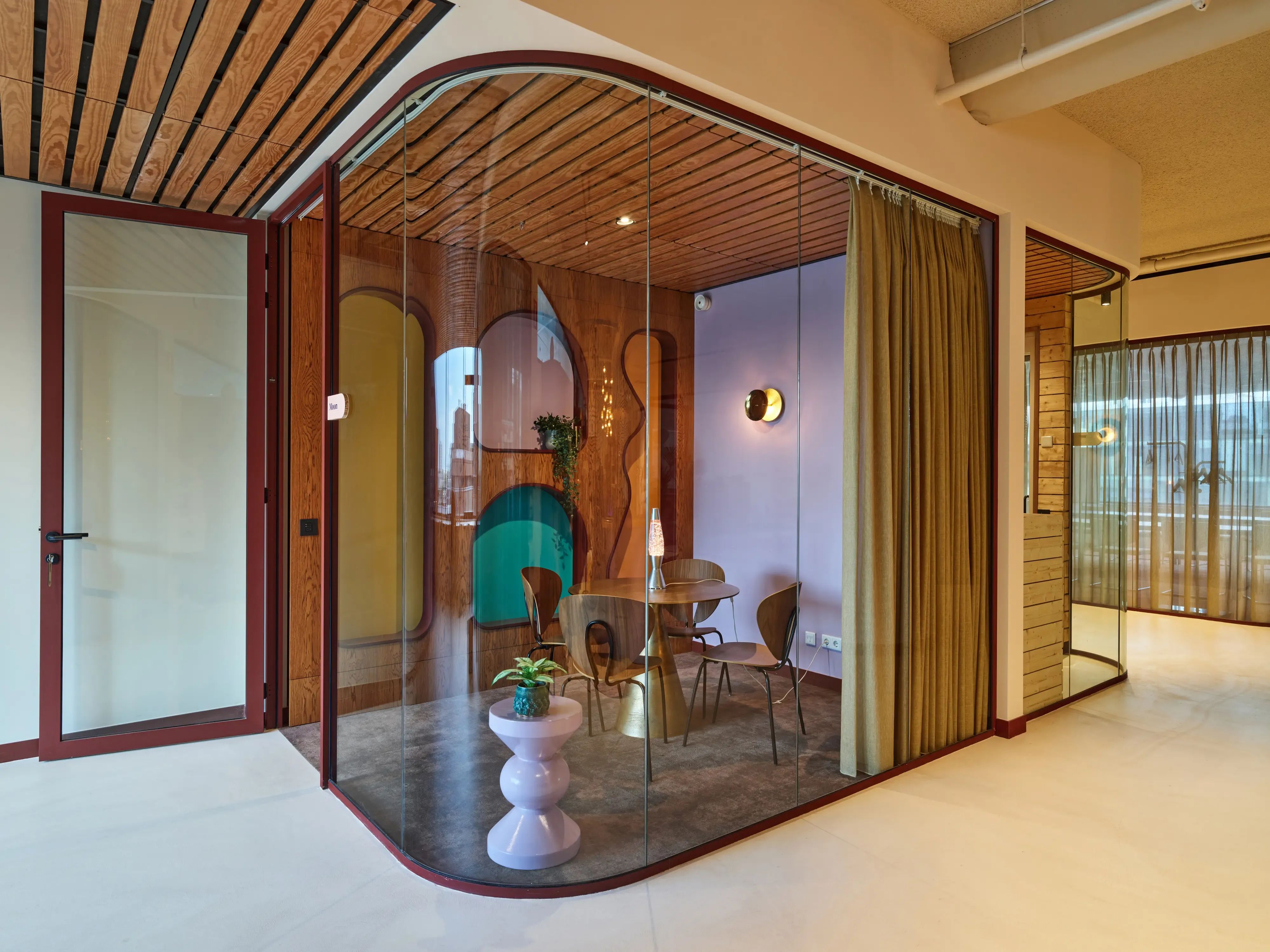 Modern kantoorinterieur met gebogen glazen wanden, houten plafond en een chique zithoek.