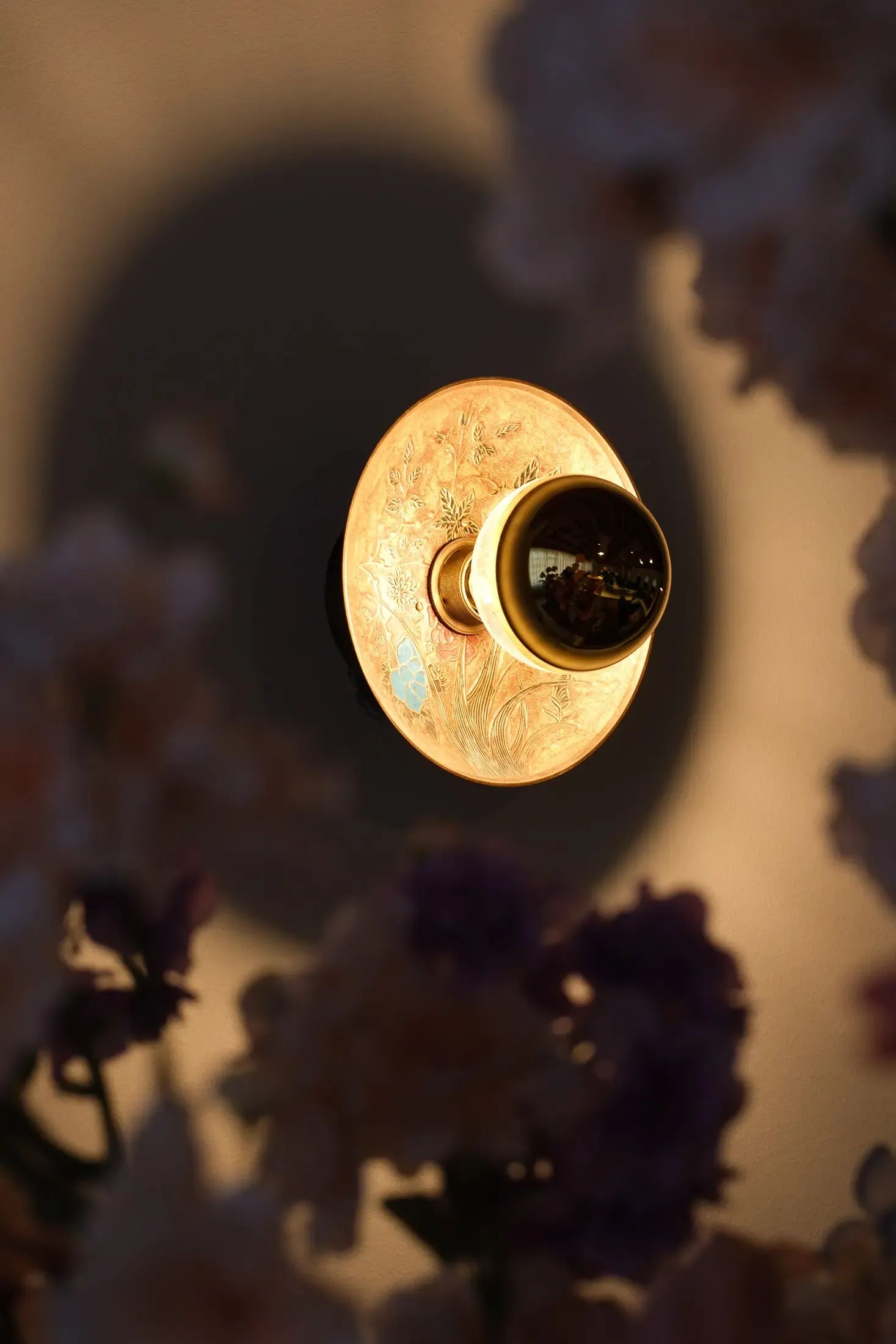 Een warme, gloeiende gloeilamp wordt omlijst door zachtgeblokte paarse en roze bloemen.
